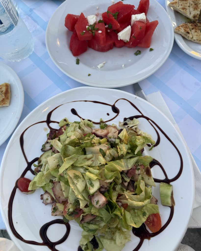 A fresh salad made with lettuce, chopped vegetables, and drizzled with balsamic reduction, served on a white plate.